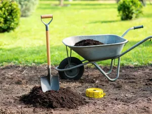 Nowy prostokątny taras betonowy w trakcie prac wykończeniowych, świeży beton i narzędzia na tle ogrodu i domu